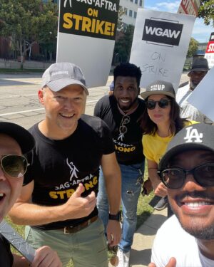 Beth Dover Instagram - I guess what we’re saying is pay us a living wage. 
*And please no more comments about why are you smiling. To clarify- We’re not having fun, it’s hot as hell, but it is nice to see old friends so we smile because we’re human not an AI bot. 
@sagaftra @wgawest #sagafteastrike #sagaftrastrong #wgastrong #payactors #paywriters #paypeoplealivingwage