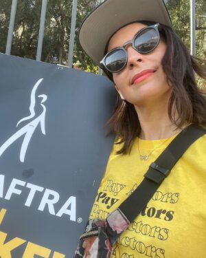 Beth Dover Instagram - I guess what we’re saying is pay us a living wage. 
*And please no more comments about why are you smiling. To clarify- We’re not having fun, it’s hot as hell, but it is nice to see old friends so we smile because we’re human not an AI bot. 
@sagaftra @wgawest #sagafteastrike #sagaftrastrong #wgastrong #payactors #paywriters #paypeoplealivingwage