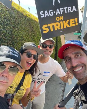 Beth Dover Instagram - I guess what we’re saying is pay us a living wage. 
*And please no more comments about why are you smiling. To clarify- We’re not having fun, it’s hot as hell, but it is nice to see old friends so we smile because we’re human not an AI bot. 
@sagaftra @wgawest #sagafteastrike #sagaftrastrong #wgastrong #payactors #paywriters #paypeoplealivingwage