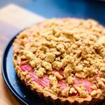 Briony May Williams Instagram - Kicking off the week with this Rhubarb Streusel Tart! Side note...how have I never made streusel before?!? It is SO GOOD!!! This latest installment in my super series of seasonal recipes is gorgeous to look at and tastes fab, definitely something to impress your family and friends. The pastry recipe is my Nana Pat’s passed down through the generations❤️The full recipe is below, please let me know if you give this a go! #seasontotaste Ingredients Pastry  225g self raising flour 120g unsalted butter, chilled Pinch of salt 50g golden caster sugar 1 egg, beaten 1 egg for egg wash Frangipane 100g unsalted butter, softened 100g golden caster sugar 2 eggs 150g ground almonds 75g plain flour 1 tsp cinnamon 1 tsp ground ginger 400g fresh rhubarb Streusel 170g self raising flour 100g light soft brown sugar 70g golden caster sugar 25g custard powder 100g salted butter, melted Method Oven on to 180C fan/200C. Make the pastry. Cut the butter into small cubes then place in a food processor with the flour and salt. Pulse until the mixture resembles bread crumbs (you can do this by hand, just rub the flour and butter together). Stir through the sugar then add the egg and mix together until it forms a soft dough. Cover and place in the fridge for 20 minutes. Make the streusel topping. Place the flour, sugars and custard powder in a bowl then whisk to combine. Pour over the melted butter (it should be warm not hot) and fold gently with a fork until you can’t see any more flour. Don’t overmix, as soon as the flour is incorporated, stop mixing. Place on a baking tray lined with parchment paper and bake for 15 minutes until golden brown. As soon as you take the streusel out of the oven, break it up using a metal spoon so you have a crumbly topping.Retrieve the pastry and roll out on a floured surface to a ¼ inch thickness. Line a 20cm tart tin with the pastry and prick the base with a fork. Scrunch up a piece of parchment paper then unfold it and place it in the pastry case then fill up with uncooked rice or baking beans. Bake for 10 minutes… ***RECIPE CONTINUED IN COMMENTS*** #recipe #rhubarb #frangipane #streusel #tart #homebaking #homebaker #baker #baking #pastry #shortcrust