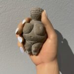 Carlota Guerrero Instagram - “Sofia Willendorf” Silicon, hair and clay (2022) @staatsgaleriestuttgart #carlotaguerrero “An apparent visitor stands serenely in a corner of the exhibition room. She has her back turned to the rest of the viewers and looks down towards a small figurine she holds with one of her hands. Titled Sofia Willendorf, the installation takes the historian and anthropologist LeRoy McDermott and Catherine Hodge's thesis from their article Decolonizing Gender: Female Vision in the Upper Paleolithic (1996) as the starting point. In the text, the authors criticize the way the first images of human bodies, the Venus figurines, have generally been interpreted “as sex objects made from a male point of view”. Instead, they argue, they were made by women and for women as a form of self-representation. Following this, the apparent distortions of the anatomy of the figurines become apt renderings if we consider the body as seen by a woman, presumably pregnant, looking down on herself. Regardless of the veracity of the argument —which seems perfectly logical and credible— the question remains; why did it take so long to consider the logical possibility that a female point of view was involved? Sofia Willendorf gives voice to that pregnant woman in the contemporary context, where past and present archetypes are confronted under the veil of an imposed male gaze the artist tries to subvert. A certain discomfort emerges while staring at the duo, ironically separated by 30,000 years gap. Originally purchased as a sex doll manufactured in China, the contemporary visitor cheerlessly exemplifies both the prevalence and the profound influence of the patriarchy." text and curation @marionavaldestorrella