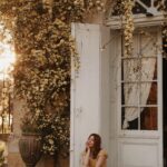 Courtney Halverson Instagram - It’s the simple things that make me most happy, and very often that involves four legs and a wagging tail. Hello from the absolutely beautiful, dreamy, and peaceful @chateau_marcellus - an 18th century château in the Bordeaux region. It’s my first time in this area of France and I have already fallen in love with the land, the flowers, and maybe a few dogs as well. Now let’s talk about it - how absolutely breathtaking is this floral draped doorway? 🌼 . . . #springflorals #romanticstyle #feminineenergy #cinematicmoments | wearing @shopdoen paired with @sezane sandals