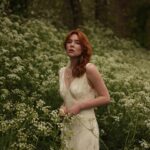 Courtney Halverson Instagram - “I always prefer wildflowers.” “I suspected as much.” 💐 My love of wildflowers and of spring and Jane Austen and romance and Beatrix Potter and The Secret Garden and of antiques and of film scores and far too many other things to name all stems (pun intended) from my mother who raised me with all of the above. Thank you for instilling in me a love of all of this so early on. I am who I am this day because of you. And if you happen to recognize the quote here you very likely are similar, so maybe we grew up loving the same things. 🌿 . . . #romanticstyle #cinematicmoments #wildflowers #ialwayspreferwildflowers #vintagevibes . . Wearing a dress from @rixo paired with beautiful clips from @eponavalley 🌿 lip color is banquette from @iliabeauty
