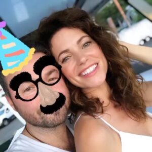 Courtney Henggeler Instagram - In an attempt shield my husband from social media and yet still celebrate his 40 years of life, I’m posting a picture of me looking radiant and my husband looking like a Eugene Levy. Because I’m nothing if not selfless partner.
Happy birthday mystery husband! I can’t believe it took you this long to turn 40. But now that you’re here, you don’t look a day over 41 and a half.  I’m lucky to have found someone who not only makes decent looking children but is enough of an alcoholic that enlisting @cakesbyjohnny to fashion a cake into an enormous bottle of Johnny Walker Black is not lost on you.  I’m so glad you were born!  Even if it was 3 years after me. Which lets be honest, doesn’t make sense.  Since I’m 30.  I love you Chad.