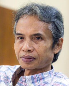 Dewi Lestari Instagram - Pencarian Satu Foto Kabar duka itu membekukan saya. Joko Pinurbo telah berpulang untuk selamanya. Seharian itu saya mengais-ngais kenangan bersama beliau. Membuka pesan WA-nya, DM-nya, lalu menelisik data foto dari tahun ke tahun, mencoba mencari satu gambar—yang saya ingat sebagai satu-satunya foto kami bersama. Sudah empat hari berlalu, foto itu tak kunjung ketemu. Saya mulai meragukan ingatan saya. Jangan-jangan, foto bersama dengan Joko Pinurbo hanyalah produk imajinasi saya belaka. Yang saya temukan cuma pertukaran pesan, yang meski tak terlalu sering, selalu berkesan. Jika Sapardi memikat saya dengan metafora indahnya, Joko Pinurbo memukau saya dengan kecerkasan, humor, dan efisiensi bahasanya. Saat berjumpa langsung, beliau cenderung pendiam, pandai menghilang dengan gesit di kerumunan. Sementara, interaksi tertulisnya terasa hangat, bahkan antusias. Namun, pesan terakhir saya pada bulan November tidak berbalas. Tampaknya beliau sedang sakit berat saat itu. Rasa-rasanya ada urusan “tak selesai” antara saya dengan Mas Jokpin, salah satunya niat saya untuk ikut kelas puisi beliau. Plus, punya foto kenangan bersamanya. Satu saja. Apa daya, batas hidup jualah yang memutus urusan itu. Saya harus puas dengan apa yang ada. Potongan pesannya. Kiriman kliping darinya. Fotonya bersama buku alumni Kaizen Writing. Semua itu kecil dibandingkan harta budaya yang ditinggalkan Joko Pinurbo bagi kita semua. Kepiawaiannya berpuisi dan bergelut dengan bahasa. Karya demi karya yang cerkas, cerdas, dan lugas. Terima kasih atas jejakmu yang luar biasa, Mas. Semoga lapang jalanmu. #JokoPinurbo #Jokpin