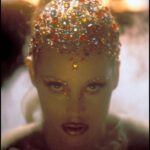 Elizabeth Berkley Instagram - Here’s a fun little #fbf and first time #showgirls trivia for you from my personal archives... when we were figuring out the look for #nomimalone for emerging from the volcano (as one does, right?!), this first pic was of course the final filmed look. But if you swipe for the second photo, this was me in the makeup chair exploring another magical headpiece. So happy we went for the multi colored rhinestones tho. What do you think, darlin? 🌈✨✨🌟🌟#imadancer #differentplaces #shejustwentdown #letmedoyournailssometimedarlin💃🏼💃🏼#itsaversayce#hair #hairstyles #hairstyle