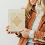 Ellie Holcomb Instagram - Hello to my fellow sojourners! It has been such a delight to hear from so many who have picked up my book, Fighting Words, and found comfort and hope in the promises of God laid out on these pages. It’s been even more wonderful hearing stories from so many people who have taken me up on the invitation to memorize scripture. Hearing how God has spoken through His word to so many of you through this book has been a gift I’ll never stop treasuring. I’m smiling wide with some of these stories running through my mind as I type this, so it is with great joy and a smile stretched across my face that I welcome you now to this of Fighting Words: 100 Days of Speaking Truth into the Darkness, coming April 16th!!! This new addition carries ten extra devotionals and one more beautifully printed scripture memory invitation. Why ten more devotionals now? Quite frankly, I didn’t realize how this book would become for me like a stake of ebenezer stones made out of paper and ink, that remind me of how God has met me, encouraged me, and transformed my forgetful heart through His word. I also realized that there were some “lifer” verses, as one of my grandmother’s calls them, that I didn’t include in the first edition. “Lifer” verses are the ones that have held me steady through the storms and shadows over the years. If they were stones, they’d be smooth from years of my carrying them around in my pocket and reaching for them in moments where I desperately needed to be reminded of mercy and truth. There have also been others that have grounded songs I’ve written and have found their way to grounding me over the past few years. I found myself in shock that I didn’t include them, so they’re here now!!! Although the book won’t be available until April, you can pre-order your copy now on my website, @amazon, or at @lifeway!! Pre-orders help retailers know how many books to order before release day, so it’s very helpful for all of your favorite authors and we thank you greatly. Stay tuned this week for more exciting release updates... 🤎
