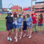 Emily Henry Instagram - Thank you all so much for coming out last night to Busch Stadium for the pre-game book club. This was one of the most special days for me of the last five years. There are no words for what it was like to get to meet so many of you. Thank you for driving and flying from all over, and for beautiful friendship bracelets, and for your letters and pencils, and for wearing your rodeo and Goode Books and Sunshine Falls Gear. It was a joy and an honor to sweat on you. A huge thank you to the Cardinals for the invitation, @juliepens for being the perfect in-conversation partner, @abergeron11 @dachejordan @daniellekeir_ and @tayhaggerty for being there for every moment of it!! I did not face my greatest fear (throwing an opening pitch) but I did face my second greatest fear (high-fiving a mascot), and that’s not nothing. 💙💙💙💙💙💜💜💜💜💜