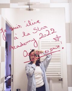 Enola Cosnier Instagram - Cette première photo c’est le début de tout ! J’ai écrit « Je suis élève à la Star Academy 2022 » le 28 juin 2022 ,en rentrant de mon audition à l’Atrium de TF1. Je faisais alors parti des 120 derniers candidats sélectionnés. Ce jour-là, je rencontrais pour la première fois Louis, sans me douter une seule seconde de la place qu’il prendrait dans mon cœur. J’ai passé l’été le plus long de ma vie, à attendre une réponse qui n’arrivait pas. Puis, arriva ce jour du 16 septembre 2022. C’est ce jour-là, en rentrant du plateau de « Danse avec les Stars », que j’écris sur mon miroir « Oui, tu es prise !», parce que j’étais la première candidate de la Star Academy 2022, annoncée en Prime Time par @nikosaliagas Je me souviens de la première fois où j’ai rencontré @luciebernardoni . Je devais faire ma prise de tonalité pour la chanson « Voilà » avec ma nouvelle répétitrice. Et j’ai vécu mon moment « Fan Girl » le plus intériorisé de ma vie quand sa caméra s’est ouverte ,et que je l’ai reconnu sans trop y croire : « Bonjour, moi c’est Lucie ! - OUI JE SAIS ! Je vous ai reconnu ! » Je ne savais pas que cette femme ( et ma @marleneschaff adorée ) deviendrait une de mes lumières réconfortantes de cette aventure, deviendrait Maman Lulu ou Mama Lucia ( quand c’est Lucie qui le dit haha). Tellement de moments, hors des caméras, qui n’appartiennent qu’à nous. Un peu comme ces photos à l’argentique, que j’ai adoré vous partager. J’ai été très ému quand j’ai découvert les premiers tirages…on était ✨beaux ensemble ✨ Merci à la production d’avoir accepté que je prenne ce petit objet avec moi au sein du château. Merci à mes camarades, et professeurs d’avoir été les meilleurs modèles photo ever 🙌🏼 Ce soir, vous pourrez nous retrouver sur TF1, à partir de 21h10 pour « Les 12 Coups de Noël ». Je vous souhaite de passer un beau réveillon , et un merveilleux Noël 🎄🎁 Je vous embrasse, Enola ⭐️ @albilouis @anishajo.music @leaa.hdd @ahcene.off @carladonaoff @chriscamalon @tianaa.off @amisse.music @canaby.jr @cenzo_thn @sr_stanislas @paola.prrn @laure.balon.coaching @pierredebrauer @yanismarshall @adelinetoniutti @michael.mmcgold