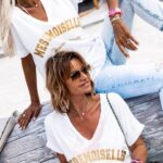Ingrid Chauvin Instagram - Le T-SHIRT MESDEMOISELLES ici décliné en blanc... un t-shirt lumineux, avec un grand col V qui fera ressortir votre bronzage. Un joli imprimé à paillettes doré. On vous propose ici 2 combos différents, Nathalie avec le JEANS BRAXTON BLEACH et des boots pour un look bohème. Ingrid avec le PANTALON MARA ROSE et les SNEAKERS ZAGO pour la touche de couleur. Un t-shirt à la dégaine oversize, qui se porte avec tous vos looks du quotidien... ❥T-SHIRT MEDEMOISELLES BLANC ❥PANTALON MARA ROSE ❥SNEAKERS ZAGO BLANC/VERT ❥ BANDANA PINK ❥ BOOTS MASHA BEIGE ❥ JEANS CG BRAXTON BLEACH ❥❥❥❥❥❥❥❥ The MESDEMOISELLES T-SHIRT here in white... a bright t-shirt with a large V-neck that will bring out your tan. A pretty golden glitter print. Here we propose 2 different combos, Nathalie with the BRAXTON BLEACH JEANS and boots for a bohemian look. Ingrid with MARA PANTALON ROSE and ZAGO SNEAKERS for a touch of colour. An oversized t-shirt that can be worn with all your everyday looks... ❥T-SHIRT MEDEMOISELLES BLANC ❥PANTALON MARA ROSE ❥SNEAKERS ZAGO BLANC/VERT ❥ BANDANA PINK ❥ BOOTS MASHA BEIGE ❥ JEANS CG BRAXTON BLEACH #ingridchauvinxgrungemama #ingridchauvin #grungemama #summerlook #look