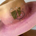 Jenna Elfman Instagram - The universe doing its thing! 🤘🏽👀🤘🏽 This hat, born from a spontaneous experiment, became a canvas for a new idea. Hand-dying the felt added that extra touch of uniquness. I hadn’t played with dye before this, so I was excited to see how it would turn out. While I was literally putting the finishing touches to this hat, I recieved a call from the lovely @therealkateceberano looking for a special gift for her dearest friend of 25 years, @jennaelfman in town for just a brief visit. Timing would be tight to make something that quick, but the universe stepped in when I shared a photo of this hat in progress. Instantly, we knew it was the perfect creation. These abstract hats aren’t for everyone, and that’s the point. They’re crafted for the ones meant to wear them. The universe works in mysterious ways, connecting us with the right person at the right time. Such a joy to meet you, Jenna! Wishing you an incredible time in Australia. And sending heaps of love to you, Kate. 🫵🏼💜 Special mention to @adamsavillebrown for being in the right spot at the right time also. 🤘🏽 #hatmaker #artist #universe #customhat #connection #friends