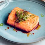 Judy Joo Instagram – Delighted my Green Chilli Glazed Salmon recipe has been featured in @cityamtravel! This dish is packed with a wonderful blend of spicy, sweet, and umami flavours. Here’s a brief run-down for you to have a go at home:

1️⃣ Glaze: Gently fry finely chopped garlic and jalapeños in vegetable oil until softened. Mix together soy sauce, brown sugar, and rice wine vinegar. Add to the pan, stir well, and simmer until reduced by half. Finish with a drizzle of sesame oil.

2️⃣ Spring Onion Salad: For the dressing, combine soy sauce, rice wine vinegar, gochugaru (Korean chilli flakes), roasted sesame oil, sesame seeds, and sugar. Cut spring onions into thin strips and immerse in ice-cold water until they crisp up. Toss in the dressing.

3️⃣ Salmon: Heat oil in a pan and fry the salmon fillets until golden brown and cooked to your preference. Arrange salmon on plates, spoon over the glaze, and garnish with the Spring Onion Salad and green chilli slices. Add a pinch of silgochu for an extra kick.

Serve with yuja pickles and a side of cooked rice. Enjoy your meal! 🍴

What recipe would you like to see next? Let me know in the comments! And don’t forget to visit my website for more delicious recipes.

For the full recipe and article, head over to #CityAM. Don’t forget to share your culinary creations with us using #GreenChilliGlazedSalmon. Happy cooking! 🍳
•
•
•
•
•
#koreanfood #salmon #chef #cheflife #chefsofinstagram #cook #cooking #chefs #fish #truecooks #ChefLife #Foodie #FoodPorn #InstaFood #Foodstagram #ChefsofInstagram #FoodPhotography #FoodGasm #FoodLover #FoodBlog #FoodPassion #FoodArt #FoodInspiration #FoodieLife #Cooking #Gourmet #FoodCulture #FoodieGram