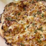 Judy Joo Instagram – I had to develop a French recipe for comedian Joe Wilkinson @gillinghamjoe on Cooking with the Stars. Thus, this tasty Tarte Flambée (Flammkuchen) recipe is really easy, quick and gloriously tasty. 🇫🇷

I over engineered the recipe, so it would be super easy for Joe to make. The dough is the measured amount to the exact size of a half sheet pan, to roll to the correct crispy thinness that you want in this pizza like tarte…

This classic dish from Alsace is known for its thin, crispy base, and a tasty savoury topping of smoky bacon, Emmental cheese, and sweet caramelised onions.  I also like to add fresh thyme leaves for a welcomed bite of fragrance and herbiness. 🥓🧀

– Use high quality extra virgin olive oil in your dough. It’ll give your crust that crunch and flavor.
– Use good quality smokey bacon and finely dice it so every bite gets its fair share.
– Stick with Emmental for your cheese. Its creamy texture and mild flavor make it the sidekick for your bacon and onions.
– Add a little sprinkle of fresh thyme and a grating of nutmeg. Trust me, your taste buds will thank you. 
– To wash down your scrumptious Flammkuchen, whip up an Alsatian wine spritz. 🍸

It’s a refreshing blend of gin, Alsace gewürztraminer, lemon juice, and golden syrup (or honey).
 
Served with a side salad loaded with baby spinach and rocket, it’s the perfect balance. 🥗

Head on over to the link in my bio 🙌
•
•
•
•
#chef #foodie #cooking #foodlove #foodart #foodblog #foodculture #delish #foodiegram #instafood #frenchfood #recipe #homecooking #flammkuchen #alsace #winespritzer #salad #bacon #emmental #cheese #onion #thyme #nutmeg #tarteflambee #chefsofinstagram