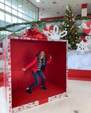 Kate Reinders Instagram - MERRY ALMOST CHRISTMAS!! 
Love, me in a huge gift box in the huge East High cafeteria… in slippers. ❤️🎁🐆