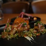 Kathryn Dunn Instagram - a date night at @windmillsbrewery 🥰🍻🫶📚 what I ate👇 🍹 The Haka - a Tiki cocktail with citrussy bright tequila, subtle notes of vanilla and hints of butterscotch, cola, and dried fig (Alex had the “Smoking Barrel” 💨🥃) 🥘 Fennel & Cumin Crusted Scallops - PERFECTLY COOKED queen scallops with fennel & cumin crust habanero buttermilk sauce 🍗 Hot ‘n Sweet Guava Chicken - sweet and spicy guava-marinated tandoori chicken 🍤 Seafood Moilee - Rainbow trout, shrimp, casava podimas, I WANT TO BATHE IN THE MOILEE SAUCE it was so good 🤤 #grandscapetx #dallasrestaurants #dallasfood #thecolony