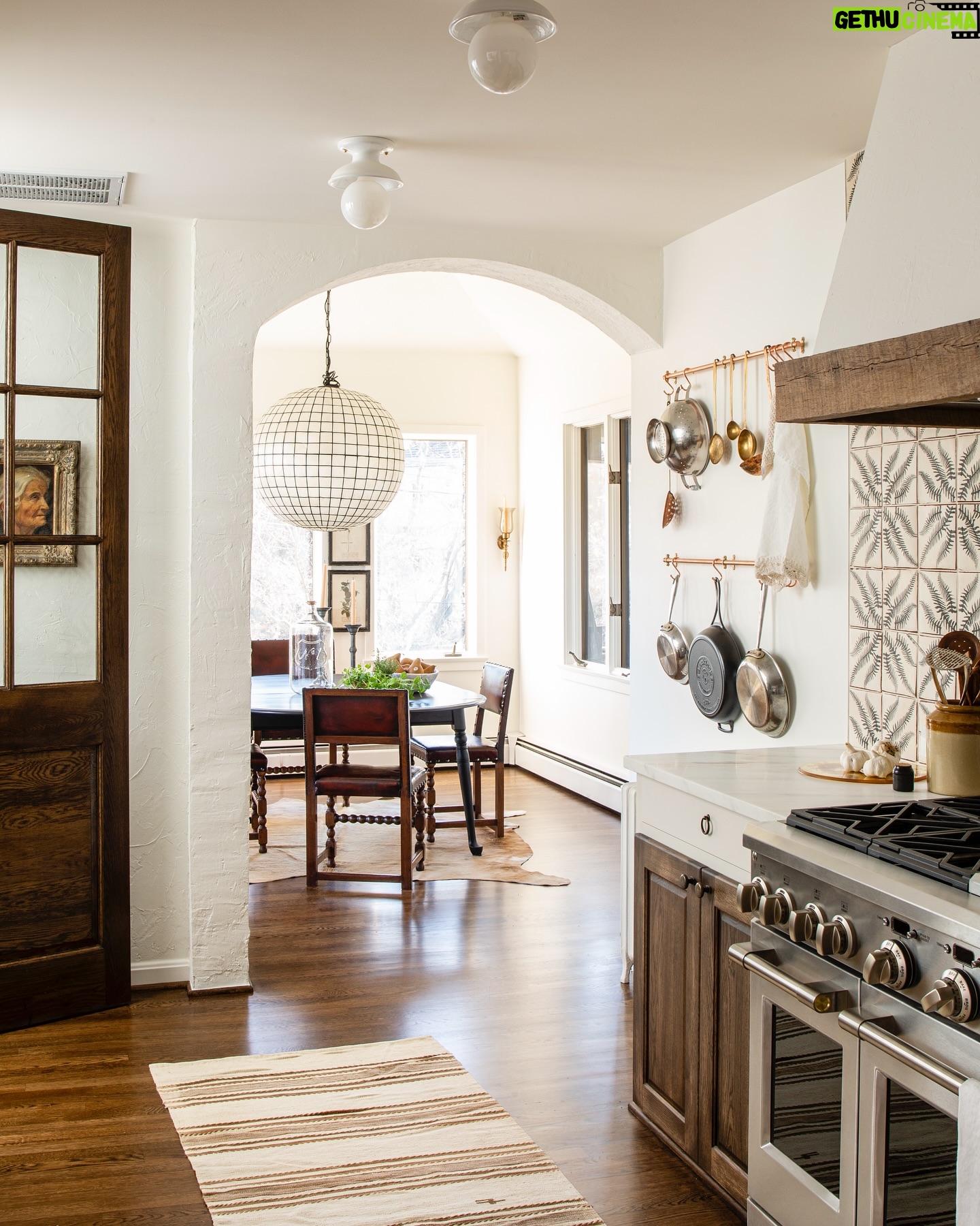 Lauren Liess Instagram - Another peek into that kitchen where you can spy the breakfast room through the archway. An antique family table became the centerpiece for the breakfast room which we decorated simply with antique Spanish colonial chairs and a hide rug for easy cleaning. A double pot rack over the old radiator is within reach of the new range. {tile is “sol di folium” from my collection with @architessa | cabinetry is the “bohemian” from my collection with @uniquekitchensandbaths and vintage runner accessories are from @laurenliessandco | renovation by @carrmichaelconstruction | design by us at Lauren Liess Interiors | photo by @helennorman for my book #feelslikehome where I share all the “whys” behind the design of the entire house }