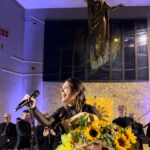 Margherita Vicario Instagram - É successa una cosa strana: il film Gloria! é uscito dallo schermo e s’é materializzato nella vita vera: abbiamo fatto un concerto in Chiesa a Molfetta, metà pubblico un po’ basito, l’altra metà trascinato dal rito. É stato divertente. Alla fine hanno rimbombato le mura ed erano tutti contenti. Ho pensato diverse volte durante queste prime tre date del tour, in questo eccesso di vitalità, che se fossi nata 4/5 secoli fa, m’avrebbero tranquillamente bruciato su un bel rogo! Chissà, magari non avrei avuto il coraggio di essere una vera strega…con la mia piantina nel vaso, lo sguardo di sguincio etcetc…Comunque ho suonato con la meravigliosa @orchestra_magna_grecia che mi ha fatto piangere 8/9 volte, come quando ho sentito per la prima volta Castagne con gli arrangiamenti di @giovannipallotti e del Maestro @patti_carmelo ❤️ Grazie a @vivoconcerti @metatronmgmt onnipresente @camilla_monge, ai miei musicisti e la mia squadra tecnica che ogni volta che li vedo sono felice di stare tra le loro mani. Ah! un grazie speciale alla ragazza che mi ha portato il CIOÉ. Dopo la Messa, ci stava. Le 3500 lire spese meglio della vita. Ci vediamo in tour❤️ PROSSIMA DATA 30 MAGGIO @ateneika_official CAGLIARI CON. BAND!!!