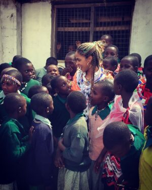Megalyn Echikunwoke Instagram - Day 2 in Kaijado at Sanare/Arroi primary school. Ahhh! Well besides the fact that when I asked to sit down and take  a picture with them I broke their bench, crashed to the ground and they all pointed and laughed for which I could hardly blame them, they also have a glorious choir that performed for us AND are educated about the impotance of effective hygiene practices to prevent communicable diseases like trachoma through @amrefhealthafrica “WASH” program which is part of the community water project from my stories. These little plastic jugs “tippy taps” tied to trees or hand and face washing stations fueled by the community water pump ensure that these kids dont get sick and can stay in school. In the first video they are welcoming me “Karibu!” (even though I broke their bench)  telling you who they are and saying “hi to USA!”