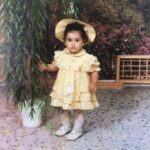 Neslihan Arslan Instagram - İlk (hatırladığım) fotoğrafçıda çekilen fotoğrafım bu.. Tam karşımda kimler vardı orası flu ama arkamda duran yalancı manzara görseli mesela dağına taşına kadar hâlâ aklımda.. Bilen bilir ki hâlâ da önümde, gözümün hizasında duranlardan daha iyi bilirim arkamda ne var ne yok.. Asla yerimde durmadığımdan, fotoğrafçı abimizi kısa süreliğine de olsa dinleyip poz vermem biraz gözleri yaşartmıştı diye de flu bi anı var yine kafamda bu arada.. Bir elbise giydirmişler, benden daha çok sevmişler o halimi, bilmediğim bir yere götürmüşler, tanımadığım bir abimiz çekildiğini hatırladığım ilk fotoğrafımı çekmiş, ben evin dışında kurallı ya da sistemli başka bi dünyayla ilk defa karşılaşmışım ki o’zaman da pek sevmemişim bu durumu falan filan… Neyse yani ez cümle; fikrim alınmadan kafam açılmaya başlamış.. Bir şeyle bazen çok ilgilenirken siz, başka çok şeyler de olabiliyor ilgilenilmesi gereken ve ıskalamak istemiyor olabiliyorsunuz onları da haliyle.. Çünkü bu bize farkında olmadan öğretilen ilk hayatta kalma bilgisi aslında; her şeyi görmen ve mümkünse değerlendirmen ya da zaten hiç elini bile sürmemen gerekir.’.. Sonra da klasik bi ‘rayına oturtma’ başlar yaş almayı anlamakla birlikte.. (Ya oturur ya da oturmaz, bu kısım başka..) Bazen bu fotoğraftaki gibi bi kal gelir/ gelebilir.. Onca şeyin ortasında aslında hafif ama onca şeyin ortasında olduğu için aslında ağır.. Fotoğraf çekildikten bir saniye sonra o yapraklarına dokunduğum çiçekle dans etmek istediğimden kendisini istem dışı yere devirmiştim.. Şu ara pek dans edesim yok ama yine de bi saksı devirirsem belki rahatlarım. İyi mi olur kötü mü olur bilmem bu arada.. Bu fotoğrafın sonrasının anısı iyiydi. Hadi başbaş..