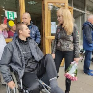 Olga Kormukhina Instagram - Ещё днём хотела поставить этот пост. Но теперь он стал ещё актуальнее. Вчера сподобились петь для наших раненых бойцов в госпитале Бурденко. Всё прошло отлично! И девочки из нашей Академии прошли на «ура» и у бойцов, и у медперсонала ( в основном женского). Пели на улице. Так, чтобы видно и слышно было во всех корпусах тем, кому не стоит пока особо передвигаться. Для нас, конечно, это был экстрим моральный, но! Чего только в жизни не бывает!Но я не об этом хочу говорить. А о наших парнях. Которых не столько мы поддерживали, сколько они поддержали в нас веру в то, что у нас достаточно храбрых и честных мужчин, готовых нас защищать. Как Володя Перфильев из 234 полка 76-й десантно- штурмовой дивизии! Да, да! Той самой! Псковской! Родной! Вова так бренчал на костыле, сидя  на коляске, что мне было реагажно и без группы.)) Потом, уже в корпусе,когда я спросила у врачей, сколько ещё нашему ( уже нашему)) Вове долечиваться, Вова сказал, не дожидаясь ответа: -Давайте быстрее! Мне назад надо! К своим! 
Ещё он всё хотел мне рассказать про девчонок - бойцов, которых враги называют «ночными ведьмами» . Не успели. Надо было бежать на Красную площадь. Но мы ещё свидимся! И на параде Победы споём! Мы теперь с ним на связи! Родня практически). 
Вова был ранен на Херсонском направлении. И вывозили его, представьте! На УАЗике! Вот что он написал:
«Буханки нужны для эвакуации раненых. Он реально нужен. 
Про фермер скажу он нужен именно в данную сезонную распутицу».
И ещё! Для мотивации: 
«Спасибо большое вам, они спасут не мало жизней». 
На фото: Володя , его товарищ ( прячет раненую руку)  и наши «новые имена» Каролина Корсакова и Майя Сперанская.
🔻🔻🔻