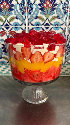 Poh Ling Yeow Instagram - Ok I finally got my shizen together this year & wrote a recipe for the retro Yeow trifle which is ‘special’ because it uses NO fresh ingredients bar the strawberries 🤔. Every time I’ve deviated ever so slightly into fancy, someone will comment “HOW INTERESTING YOU USED SOUR CHERRIES & HOMEMADE CUSTARD THIS YEAR” - code for “Why did you turn this into something unpredictable”. Anyhoo, i guess the moral is if it ain’t broke - enjoy! Merry Holidays everyone!!! ♥️⭐️ 

YEOW FAM RETRO TRIFLE
3 packets 🍓 or raspberry crystals 
4 Tbs powdered gelatine or 10g sheet gelatine 
1 x 6 pack mini jam rollettes, sliced 1.5cm
2 punnets strawberries, slice enough to cover the diameter of the trifle bowl, cut the rest into 1cm cubes. 
825g tin sliced peaches, drained 
2-3 cups custard (powdered kind - make using packet instructions or u can use home made creme patt of course) 
1 cup thickened cream, whipped with 2 Tbs full caster sugar & 1 tsp vanilla or strawberry essence until medium - stiff peaks

Make 2 packets of the jelly following the packet instructions but add the extra gelatine. Stir until all the crystals are dissolved then pour into a flat 25x20cm-ish tray or dish. Chill in fridge for 2 hours or until set firmly. 

Make the remaining packet of jelly using regular packet instructions. Set aside. 

Arrange the jam rollettes on the bottom of the triffle bowl (about 4L capacity). Pour the warm jelly mix over the rollettes making sure all the pieces are soaked through. 

Layer as follows: 1/2 of the custard, peaches, remaining 1/2 of the custard, strawberries, whipped vanilla cream. To finish, slice up your finger jello into cubes and rain them over the cream piling them as high as possible. Chill for 2 hours so the jelly in the bottom is set. Serve with a smol shovel, dive in and hope jelly cubes don’t wind up bouncing all over your mum’s carpet 🤭😚