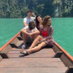 Rita Ferro Rodrigues Instagram - Day 7🤍 Atirat danphattharaworawar mais conhecido por BB é o proprietário deste paraíso . Um residente da vila local, nasceu numa família pobre mas conseguiu licenciar - se em engenharia em Bangkok onde começou a vida profissional , tendo mais tarde a oportunidade de trabalhar no estrangeiro . Sentiu sempre , porém, o dever moral de voltar para a terra onde tinha nascido e de ajudar o seu povo a ter uma vida melhor. Resolveu dedicar - se ao turismo : no @resort500rai só emprega residentes locais e … e tudo o que se consome é da região. Dizem -me que é uma figura singular, gostava imenso de o ter conhecido mas não estava cá por estes dias. Mergulhámos no lago morno e límpido, andámos de caiaque e fizemos paddle, fomos em Safari pelos margens à procura da bicharada que vive livre no seu habitat, não vimos elefantes mas um bambi olhou -nos longamente nos olhos, curioso e sem medo, antes de desaparecer pela folhagem da floresta. Preocupada com a desilusão dos pintainhos por não verem elefantes devo ter baixado o sobrolho por instantes , até ouvir o Duda dizer : “ eu não preciso de os ver para estar feliz. Sei que estão por aí naquelas árvores e saber isso chega -me” É isso filho. Às vezes não precisamos de ver, apenas de sentir. Sei que uma das preocupações do Atirat ( voltando ao dono do @resort500rai ) é ensinar inglês ao staff, pois a maioria não sabe quase nem uma palavra. Por mim não era preciso . Comunicámos por gestos e sorrisos. - e eu que estou cansada de palavras vazias - apreciei esta poupança no verbo e consequente investimento nos gestos e atitudes. Mas o melhor momento do dia foi com a minha filha Leonor, no barco, quando deitadas ao pôr do sol , demos as mãos em silêncio . ‘Cause I, I I don’t know how to feel But I wanna try I don’t know how to feel But someday, I might Billie Eilish Daqui a poucas horas abandonamos - a muito custo - este lugar encantado. Disse -lhes para guardarem tudo na retina do coração , que é onde se vê sempre melhor. Até amanhã 🫶🏽 num novo destino tailandês. O penúltimo desta aventura da mãe e dos seus pintainhos. Que para mim serão sempre pequeninos. Sempre. 🐣🐣🐣 #bestravel #bestravelviagens