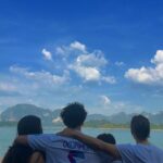 Rita Ferro Rodrigues Instagram - Day 7🤍 Atirat danphattharaworawar mais conhecido por BB é o proprietário deste paraíso . Um residente da vila local, nasceu numa família pobre mas conseguiu licenciar - se em engenharia em Bangkok onde começou a vida profissional , tendo mais tarde a oportunidade de trabalhar no estrangeiro . Sentiu sempre , porém, o dever moral de voltar para a terra onde tinha nascido e de ajudar o seu povo a ter uma vida melhor. Resolveu dedicar - se ao turismo : no @resort500rai só emprega residentes locais e … e tudo o que se consome é da região. Dizem -me que é uma figura singular, gostava imenso de o ter conhecido mas não estava cá por estes dias. Mergulhámos no lago morno e límpido, andámos de caiaque e fizemos paddle, fomos em Safari pelos margens à procura da bicharada que vive livre no seu habitat, não vimos elefantes mas um bambi olhou -nos longamente nos olhos, curioso e sem medo, antes de desaparecer pela folhagem da floresta. Preocupada com a desilusão dos pintainhos por não verem elefantes devo ter baixado o sobrolho por instantes , até ouvir o Duda dizer : “ eu não preciso de os ver para estar feliz. Sei que estão por aí naquelas árvores e saber isso chega -me” É isso filho. Às vezes não precisamos de ver, apenas de sentir. Sei que uma das preocupações do Atirat ( voltando ao dono do @resort500rai ) é ensinar inglês ao staff, pois a maioria não sabe quase nem uma palavra. Por mim não era preciso . Comunicámos por gestos e sorrisos. - e eu que estou cansada de palavras vazias - apreciei esta poupança no verbo e consequente investimento nos gestos e atitudes. Mas o melhor momento do dia foi com a minha filha Leonor, no barco, quando deitadas ao pôr do sol , demos as mãos em silêncio . ‘Cause I, I I don’t know how to feel But I wanna try I don’t know how to feel But someday, I might Billie Eilish Daqui a poucas horas abandonamos - a muito custo - este lugar encantado. Disse -lhes para guardarem tudo na retina do coração , que é onde se vê sempre melhor. Até amanhã 🫶🏽 num novo destino tailandês. O penúltimo desta aventura da mãe e dos seus pintainhos. Que para mim serão sempre pequeninos. Sempre. 🐣🐣🐣 #bestravel #bestravelviagens