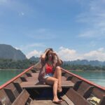 Rita Ferro Rodrigues Instagram - Day 7🤍 Atirat danphattharaworawar mais conhecido por BB é o proprietário deste paraíso . Um residente da vila local, nasceu numa família pobre mas conseguiu licenciar - se em engenharia em Bangkok onde começou a vida profissional , tendo mais tarde a oportunidade de trabalhar no estrangeiro . Sentiu sempre , porém, o dever moral de voltar para a terra onde tinha nascido e de ajudar o seu povo a ter uma vida melhor. Resolveu dedicar - se ao turismo : no @resort500rai só emprega residentes locais e … e tudo o que se consome é da região. Dizem -me que é uma figura singular, gostava imenso de o ter conhecido mas não estava cá por estes dias. Mergulhámos no lago morno e límpido, andámos de caiaque e fizemos paddle, fomos em Safari pelos margens à procura da bicharada que vive livre no seu habitat, não vimos elefantes mas um bambi olhou -nos longamente nos olhos, curioso e sem medo, antes de desaparecer pela folhagem da floresta. Preocupada com a desilusão dos pintainhos por não verem elefantes devo ter baixado o sobrolho por instantes , até ouvir o Duda dizer : “ eu não preciso de os ver para estar feliz. Sei que estão por aí naquelas árvores e saber isso chega -me” É isso filho. Às vezes não precisamos de ver, apenas de sentir. Sei que uma das preocupações do Atirat ( voltando ao dono do @resort500rai ) é ensinar inglês ao staff, pois a maioria não sabe quase nem uma palavra. Por mim não era preciso . Comunicámos por gestos e sorrisos. - e eu que estou cansada de palavras vazias - apreciei esta poupança no verbo e consequente investimento nos gestos e atitudes. Mas o melhor momento do dia foi com a minha filha Leonor, no barco, quando deitadas ao pôr do sol , demos as mãos em silêncio . ‘Cause I, I I don’t know how to feel But I wanna try I don’t know how to feel But someday, I might Billie Eilish Daqui a poucas horas abandonamos - a muito custo - este lugar encantado. Disse -lhes para guardarem tudo na retina do coração , que é onde se vê sempre melhor. Até amanhã 🫶🏽 num novo destino tailandês. O penúltimo desta aventura da mãe e dos seus pintainhos. Que para mim serão sempre pequeninos. Sempre. 🐣🐣🐣 #bestravel #bestravelviagens