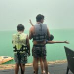 Rita Ferro Rodrigues Instagram - Dia 6 🤍 Como começar ? Antes de chegarmos ao lugar mais bonito que os meus olhos alguma vez vislumbraram fizemos uma viagem de duas horas de barco - porque este lugar situa-se no Parque Nacional Khao Sok , província de Surat Thani (Tailândia) e inclui os 165 km² do Lago Cheow Lan contido pela represa Ratchaprapha. Deve ser aqui que habitam todas as divindades da natureza - só pode ser aqui o seu refúgio - pois não é possível tanta beleza existir sem um qualquer toque divino. Aguardámos pelo barco com uma futebolada com crianças locais, fizemos a viagem com Sol, por entre várias tonalidades de água quente e doce que abraça escarpas magníficas e verdejantes, todas as cores da natureza em intensidade máxima, um espectáculo de poder do natural em bruto, uma parte do planeta muito preservada do toque humano. Chegámos ao @resort500rai com uma tempestade tropical a aproximar -se, bela e breve, e os pintainhos loucos de alegria, aos mergulhos à chuva , um descontrole de emoções ( tão bom !) perante o cenário de sonho. Totalmente sustentável , este resort constituído por pequenas , simples e confortáveis casinhas de madeira, munido de painéis solares, caiaques ( só saímos dos quartos nestes barcos que estão atracados à frente de cada habitação ) está totalmente integrado no parque natural. A partir das 22 h exige -se silêncio, o lema é “ disconnect to connect “ e por isso não há televisão e o serviço de wi - fi é muito limitado. A comida Thai é toda aqui confecionada - óptima - porque estamos no meio da selva, habitat de macacos, elefantes e outra bicharada fabulosa que vive em ambiente selvagem e que cumprimentaremos amanhã, numa das actividades que o resort proporciona. Não existe civilização por perto. Magia total ✨ Pintainhos e mãe vão dormir exaustos mas felizes. Amanhã é outro dia, cá estaremos para partilhar convosco. Muito amor aqui do Lago ❤️ #bestravel #bestravelviagens
