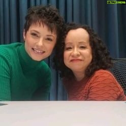 Rosanne Mulholland Instagram - É com muita alegria que estamos trazendo ao mundo o videocast "A Grande Beleza ", fruto de uma grande amizade e longas e profundas conversas regadas a vinho rosé. Ao longo do tempo nós percebemos como essas trocas são enriquecedoras e como determinadas experiências poderiam ser vivenciadas de maneiras tão diversas porque, mesmo se tratando de duas mulheres, somos vistas pelo mundo de maneiras diferentes. Somos duas mulheres de pele clara, viemos da mesma camada social, somos artistas mas, enquanto uma é uma mulher com deficiência, a outra é uma mulher sem deficiência. Enquanto uma de nós é lida como dentro de um padrão estético, a outra é tida como fora desse mesmo padrão. E é esse julgamento que fazem dos nossos corpos que produz experiências tão diferentes dentro desse imenso espectro que é ser mulher. Nossa convivência nos fez compreender que vivenciamos a interseccionalidade esse tempo todo mesmo que esse termo tenha entrado em nossas vidas tempos depois. Por isso se tornou uma necessidade para nós expandir essas trocas e compartilhar nossas vivências com outras tantas, potentes, únicas, encantadoras e diversas mulheres. Por isso criamos "A Grande Beleza" e queremos amplificar para o mundo que "A Grande Beleza está nas múltiplas possibilidades de ser mulher. " #PraTodosVerem : vídeo com Rosanne, mulher branca, com cabelos castanhos e curtos. Ela veste uma blusa verde de manga comprida e gola alta. Ao seu lado está Andréa, mulher de pele clara com cabelos castanhos, cacheados, na altura dos ombros. Ela veste uma blusa de manga curta cor de telha. Elas estão em um estúdio com paredes esverdeadas e sentadas na lateral de uma mesa branca. Ao fundo uma TV com a logomarca de A Grande Beleza. Fim da descrição.