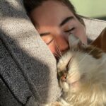 Sarah Desjardins Instagram - Kim is sitting in my lap as I write this. I wouldn’t be able to do it otherwise. 23 years is almost unheard of for a cat. She stuck by my side as long as she possibly could. She knew I needed her more than I did. Today I had to let the love of my life go. I will never forget every second I spent with her. Kim may have been a cat but she behaved like a human being. She understood all my emotions and gave me so much unconditional love and empathy. She spooned with me in the mornings, she curled up on my chest when she could sense that I was sad, she just wanted to be touching me at all times to be honest with you…even if she sat next to me and just placed her paw on my hand. Since I was a kid we were always in it together. She’s moved with me through every city and season of my life. I’m so deeply grateful to have gotten to share it with a little lady this special. My life has always contained a lot of heaviness and Kim has willingly carried that load with me. As of late it’s felt as though my nervous system is finally nearing a point where it’s ready to release some of that weight…no doubt in part to her. A new chapter lies ahead and in the most devastating way it almost makes sense that she wasn’t meant to come with me. (I’m crying now and Kim has migrated to rubbing against my face) While it will be impossible not to feel her absence I will also always carry the profound impact she had on my entire being, the way I love and how I walk through life. Goodbye Kim ♥️ You will be with me forever. watch the last slide till the end. I just found it and it kills me 🤍