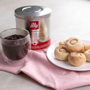 Silvia Colloca Instagram - A little sweet moment, with all the Italian flaire. We do hot chocolate thick and dense…. Highly addictive… add a touch of @illyinaustralia for an extra boost! 
@silviasitalianmasterclass 

Italian Style Espresso Hot Chocolate with Almond Cookies
Ingredients

For the hot chocolate 

Serves 2

2 tbs Dutch cocoa powder 
80 g (1/3 cup) caster sugar
2 scant tablespoons cornflour
1/2 teaspoon vanilla bean paste
500 ml (2 cups) milk
2 shots of freshly brewed espresso coffee
2 tablespoons dark chocolate chips 

Method

Combine the cocoa, caster sugar, cornflour, vanilla  in a small saucepan.

Pour in 3 tablespoons of the milk and whisk until the mixture turns into a sticky, dark brown paste. Slowly add the rest of the milk, whisking enthusiastically as you go to prevent any lumps from forming. Add the espresso shots and stir through.

Place the saucepan over medium heat and bring to a simmer, stirring constantly with a wooden spoon or spatula. Reduce the heat to low, add the chocolate chips and cook, stirring, for 2–3 minutes or until the hot chocolate starts to thicken. Turn off the heat, serve hot.

For the almond cookies

makes 18

2 egg whites, at room temperature
170 g caster sugar, plus extra for rolling the cookies in
300 g almond meal
2 teaspoons vanilla extract or paste
finely grated zest of 1 lemon
18 blanched almonds
Method

Preheat your oven to 160°C fan forced, 180 C conventional

Place almond meal in a large bowl, add vanilla, lemon zest and egg whites and mix with your hands to form a paste.

Shape the paste into balls, roll them in the sugar, then gently push your thumb into the middle of each ball and top with a blanched almond 

Place the cookies in a baking tray lined with baking paper and bake for 18-20 minutes or until the base of the amaretti looks firm and slightly golden.

Cool them on a rack for at least 10 minutes before eating