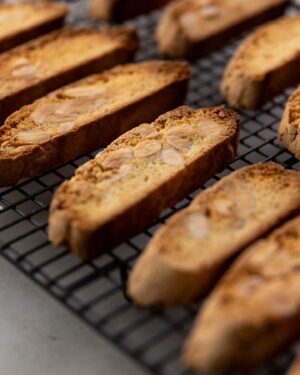 Silvia Colloca Instagram - The most loved Italian biscuits: biscotti!
Crunchy, nutty, sweet… perfect for dunking!
Made with beautiful @mulinocaputo flour and Colavita olive oil, distributed in Australia by the amazing Basile family, long time collaborator of mine @basile_imports 

Lemon and Almond Twice Baked Tuscan Biscotti
Ingredients

2 eggs
3 egg yolks
350 g caster sugar
1 teaspoon vanilla paste or extract
450 g self-raising flour, sifted (or plain flour mixed with 1 tablespoon of baking powder)
1 tbs baking powder 
1 tbs extra virgin olive oil
pinch of salt flakes
finely grated zest of 2 lemons
200 g blanched almonds
Preheat your oven to 190°C (170°C fan-forced) and line a large baking tray with baking paper.
Place the eggs, egg yolks, sugar and vanilla in a mixing bowl and beat until pale and creamy. Add the flour,baking powder  oil, salt and lemon zest and then the nuts. Shape the dough with floured hands to form two logs. Place the logs on the prepared tray, spaced well apart to allow for spreading, and bake for 25–30 minutes or until well risen and pale golden. 
Remove from the oven and cool at room temperature for 3–5 minutes, then cut them on an angle into 1–1.5 cm thick slices. Make sure you use a very sharp serrated knife to ensure neat slices. You will notice than the inside of the biscuits are still a little wet – this is fine. 
Arrange the slices on the lined tray and return to the oven for 5 minutes. Turn them over and toast for a further 15 minutes or until crisp and golden. Cool at room temperature, then serve with gelato, coffee or your favourite dessert wine. Any leftover tozzetti will keep in an airtight container for up to 2 weeks.

Watch @silviasitalianmasterclass on @channel10au and @10playau