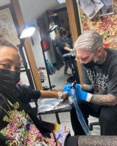 Thandiwe Newton Instagram - NOW I’m home. Got my post @westworldhbo Season 4 ink done by my homeboy @miles_chappers Every milestone is marked by Miles. Booker came along to watch. He designed a tattoo for me too, thank you baby. @frithsttattoo ☠️ go hard or go home Xx Thandiwe Oh yeah - wearing @ashish dope hoodie and @chanelofficial watch @bella_freud sparkly leggings that you can’t see 😋 And @sacaiofficial boots that I want grafted onto my ankles like permanent hooves. I pissed IN the f***ing toilet 🙏🏽