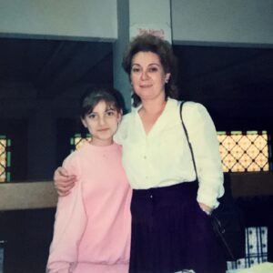 Zeynep Kumral Instagram - Çocukluğumun bir kısmı çalıştığın bankada geçti. Okuldan eve gelir, üstümü değiştirir, senin öğle tatilini kaçırmamak için bankaya koşarak  gelirdim. Her maaş aldığın gün beni ya o küçük beyaz ahşap dükkana İskender yemeğe götürürdün ya da çiçek ızgaraya köfte yemeğe. Gittiğin gün Heykelde yürüdüm biraz. Setbaşı köprüsünde durdum dereye baktım, bana kıyafet aldığın bir mağaza vardı “Rafet”, kapanmış o yerine başka bir şey açmışlar, postanenin önünden geçtim... simli yılbaşı kartları alırdık oradan. Kimin için alırdım, kime gönderirdim bilmiyorum çünkü dünya üzerinde sizden başka tanıdığım yoktu. Biraz daha yürüdüm Tophane’ye geldim. Başımı kaldırıp uzun uzun baktım, sanki ilk defa görüyormuşum gibi geldi. İskender yemeğe gittiğimiz dükkanın önünden de geçtim, orası hala aynı... Hala küçücük ve hala beyaz... Ahmet Vefik Paşa Sahnesi önünde durdum. Tüm hayatımı değiştiren bu binaya da uzun uzun baktım. Tiyatro okuyacağım dediğimde ettiğimiz kavgayı ve sonrasında durmadan devam eden tartışmalarımızı hatırladım. Bu benim okulu kazanıp evi terk etmeme kadar devam etti. Sen benim bankacı ya da resim öğretmeni olmamı istiyordun, ben ise hikayemle yüzleşme derdindeydim. Küstük... ama kıyamadın, en sevdiğin pembe saten yün yorganı da kattın yanıma.... İzmir’in ayazında üşümeyeyim diye. Sen öyle severdin. Söylemez eylemde bulunurdun. Her bayramda, nişanda, düğünde benim için özene bezene diktiğin elbiselerden biliyorum bunu. Bir giyimlik elbiselerdi onlar, ya ağaca tırmanırken yırtardım ya da koşarken bacağıma dolanıyor diye keserdim eteklerini. Ağlardın, bir daha bir şey yok sana derdin. Bir sonraki bayram yine dikerdin. Dedim ya kıyamazdın...

Bu fotoğrafın çekildiği anı hatırlıyorum. Halam, annen ( annem ) yeni vefat etmişti. İkimiz de kırılgandık, hassastık. Çok konuşmuyorduk. Çalışma arkadaşların üstümüze titriyordu.  İş çıkışında bir tanesi sizin şöyle güzel bir fotoğrafınızı çekeyim demişti. Sen de makyajım yok ama demiştin. Makyajsız çıkmazdın, her koşulda göz kalemini çeker rujunu sürerdin. Ama yastaydık ve makyajın yoktu işte. Zoraki bir tebessüm var yüzümüzde. Sen yorgun görünüyorsun daha çok. Ama kıramadın, sarıldın, tebessüm ettin...    