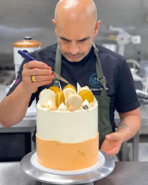 Adriano Zumbo Instagram - The intense concentration 🤔😅
A delicious vanilla cake, chocolate ganache, coated in luscious buttercream and topped with popcorn and caramel Zumbarons, chocolate pieces and gold leaf 🍃
Order your occasion cake at www.zumbotest.com ❣️
#zumbo #zumbotest #noosa #noosaville #sunshinecoast #occasioncake #21st #peach