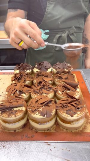 Adriano Zumbo Instagram - Building our tiramisu in our Zumbo glasses ☕️
Coffee and milk chocolate cremeaux 
Lightened whipped mascarpone 
Savoiardi sponge soaked in coffee 
Shaved dark chocolate
Can’t beat a good tiramisu 👌🏼
#zumbo #zumbotest #noosaville #sunshinecoast #noosa #tiramisu #classic