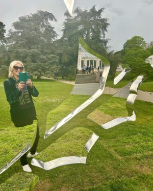 Anneka Rice Instagram - Can’t stop thinking about the Mark Quinn exhibition at Kew Gardens. His sculptures are beautiful - massive giant mirrored plants - which emerge from the sumptuous green lushness around. Here I am disappearing into a reflective frond. It really makes you feel part of the landscape as your reflection  disappears into it. There’s sex thrown  in too with a massive glistening red orchid. I really recommend a visit. @kewgardens #kew @marcquinnart