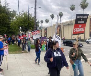 Brooke Smith Instagram - @wgawest picket line today at WB… saw this guy with the lotion sign & had to get a shot with it! #tedlasso showed up to  support, so did @_kismetcollective_ - they let protesters use their bathroom, gave out free water & coffee, and the guy on the motorcycle kept spirits up! @sagaftra