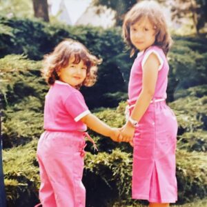 Carima Amarouche Instagram - Je sais que cette photo est un peu… comment dire? flippante,digne de American horror story, mon père m’avait coupé les cheveux ce jour là! La cause Chopage de poux! Rien d’original à côté de ma pause et ma robe! Si tu regarde bien on peut voir le seum dans mon sourire et ma pupille!!!( Zoom) mais j’adore cette photo!!! elle était accrochée dans le salon de mes grands-parents. l’autre je suis avec ma@petite soeur @noraamourache et ouais! ma mère kiffait le rose. Déjà Petite on m’appelait Karimouche ou Karoum pour mon père. On chantait avec mes sœurs et mes cousines devant le miroir avec notre télécommande en guise de micro. Depuis je chante devant vous avec un vrai micro! 🥳et quand le traque me prend j’imagine que c’est une télécommande. Merci infiniment pour tout vos retours et vos messages d’amour Merci  d’être là dans les salles et de donner vie à cette tournée✨✨Hâte de vous retrouver  le 16 Décembre à ❤️‍🔥LA MAROQUINERIE❤️‍🔥pour fêter mon album « Folies Berbères » avec en première partie la princesse @maiabarouh ✨vous pouvez venir avec vos télécommandes!  Qui chantait avec sa télécommande ??? souvenirdudimanche ! #letempsfile #foliesberberes @bluelineprod #concert #live #souvenir @nissa_officiel_ @mariebritsch_