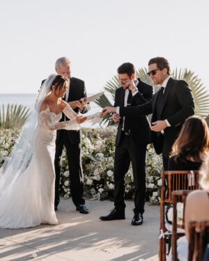 Cassie DiLaura Instagram - wedding details • part three • the ceremony 

• the kiss 😘 I laugh now at how much thought went into this moment beforehand… is everyone out of the way? do I go on the outside of your nose? where’s my arm/hand go? 😂 best part was my brother shouting “alright, that’s enough.”
• last minute decision to add rose petals to line the aisles 👌🏼 @blushnroses.cabo 
• I almost didn’t even make it to the ceremony (story for the next post 😅) but I must have taken 25 deep breaths during this “walk” and somehow managed to not get that veil snatched off the top of my head 😂  I met both my mom and dad at the bottom of the stairs too 🥰 
• 🥲 @brettlazar 🥲
•66 of our favorite people ♥️♥️♥️   @photobyjulieta & @danieljireh working their magic ✨✨
•shoutout to our free officiant!!!! thank you dad #2!!!! ♥️
•shoutout to our 2-year-old ring bearer @therealleebow 😂
•thank you @gerardodiazviolinis for the beautiful, beautiful, beautiful violin music. all of me wanted to cry but I couldn’t ruin my makeup LOL 🎻 
•2/3 of my flower girls 💐 thank you @azazieofficial for the most gorgeous dresses!!! the girls whirled and twirled all night in them 🤍
•the best photo of the wedding… dad catchin’ some 💤 because weddings are exhausting 😂

#wedding #thecape #weddingdetails #florals #weddingvenue #weddingflowers #weddingdress #weddingdecor #weddinginspo #cabosanlucas #bride #groom #weddingviolin #cabo
