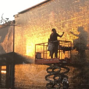 Claudia Black Instagram - #nofilter I came by this vision driving in my car and snapped this moment through the windshield. To the artist's right, another artist on another cherry picker. To his right, tourists on the sidewalk below, taking selfies nestled in between a crudely painted pair of wings on a lower wall. I watched as people walked past the men painting. Were they seeing this? Was anyone sharing this moment with me? Two male artists up high, bathed in a God-like gold? I turned the corner, parked my car and walked briskly back to the wall and these men. Could I get a better picture? The light had faded, my heart pounding, the moment passed, and I needed to share it. "Excuse me," I called up, smiling, shining to this man on the left. He was wearing ear buds though could hear me."I don't mean to disturb you from your work, I just wanted to show you something." " Sure," he responded as he lowered the cherry picker down toward me. I held up my phone like a slightly shy child with my little offering- this moment I'd caught of him in glistening pixels. Embarrassed that I'd stopped his work, hoping it would be worth it, "I just wanted you to see this. People  always take photos with those wings over there and they're ignoring the magic right here." "It doesn't matter what we paint, they're always looking at those wings." "Well," I replied," not only are they missing out on what you're painting, they missed this too. You are an artist and you are also the art. You ARE the art."
He looked at me like,'o-key cray-zee' I started to shuffle off and thought, I'll still show the painter on the right, so I held up my picture to him again, this  little child, as if my subtext was screaming, " please look! Please see! I'm trying to show you how beautiful you are!" "Cool," he nodded.  I had somehow failed the attempted connection with these men. I couldn't share what I'd yearned to with them. Though the beauty of that moment was dominating my heart space. I got some felafel and now share it with you. #citylife