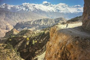Cory Richards Instagram - Words by Ben Ayers @jetbutterflies // In the wide desert of Upper Mustang, the road planes along canyon walls and dry mountainsides dotted with hundreds of unspeakably ancient human-made caves. The light plays a slow game of chase with the shadows cast by the highest mountains on the planet, now behind us. We sweep the corners wide, drawn to cliff-edges teetering above the braided Kali Gandaki River below. We don’t know where to look – the road, the layers of tortured mountains, or the sand-castle parapets of rock and mud towering above us.
 
Instead, we watch the oncoming frame-bent jeeps as they roaring around the blind corners on bald tires. In Tsarang, the drivers share a rough kindness with us. We play snooker, a game we don’t know. Cory tries and fails to find a tutorial on YouTube. Nursing warm cans of beer, we realize the drivers don’t know how to play either.
 
The evening passes in one long, impossible game of scratches and flubs until the young man running the hall flicks the light switch and kicks us out into the cold, thin air of a star-streaked night.  @vacheronconstantin