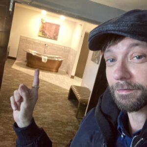 DJ Qualls Instagram - I’m back to work! These past 9 months of filming shutdown have been hard. I’ve felt isolated and, at times, like a man without a purpose. Being here right now feels pretty damn good. You can’t see it, but I’m big smiling underneath that mask. You also can’t see that I’m wearing underwear, long underwear, two pairs of socks, a thermal shirt, T-shirt, a flannel and a hoodie underneath that coat. 

I arrived in Montana in the dark of night and woke up bleary eyed to all this beauty. The accommodations aren’t so bad, either. Giant copper bath tub ? ✔️ Fireplace with The Great British Baking Show playing above? ✔️ ✔️. Thanks @katebosworth for including me on this adventure. Haven’t worked yet, but already having a great time.  #bigskycountry #montana #filmmaking #actor #backtowork
