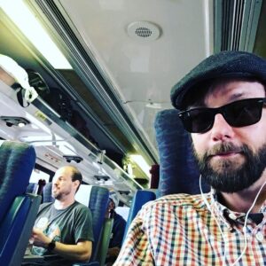 DJ Qualls Instagram - On the train to San Diego for Comic Con. Getting a ton of weird looks. Took a selfie and saw that this hat/glasses/beard combo looks like I’m attempting to wear a disguise—the kind of disguise worn in low budget comedies. @lydiahearst’s trip down was much more glamorous than this. I wonder if it’s a secret we are working together? #comiccon #sdcomiccon possible #spoileralert #themanbesidemetalkslikePaulLynde. #znation