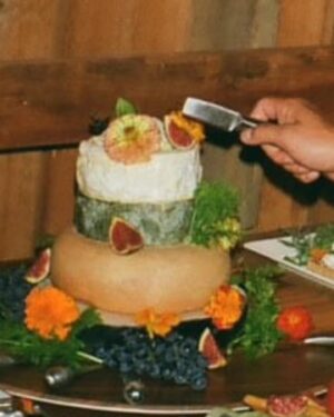 Ennis Esmer Instagram - I don’t think enough guests at the @evanyrosen-@james_hartnett wedding fully grasped or appreciated that this cake was made by stacking 4 wheels of increasingly decadent cheeses and adorning them with figs, flowers and grapes. Thank you @fudagraphy for capturing this moment that even @slorrin missed. #spoonwedding