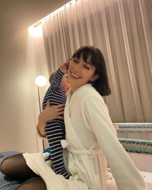 Geraldine Hakewill Instagram - An appreciation post for our baby, who has put up with (very lovely) babysitters, a (very lovely) hotel, and two very tired and distracted parents. We love you mate. And we love @melbfilmfest 🌟 thanks for looking after all of us and our film. Next stop, @cinefestoz 🐓

ID: Image one - a woman in a hotel robe holds a baby. She is smiling with her eyes closed as he plays with her hair. 
Image two - a man sits in a chair with a baby balanced on his head. He looks up at the baby, making an excited face. Behind them is a view of the Melbourne skyline.