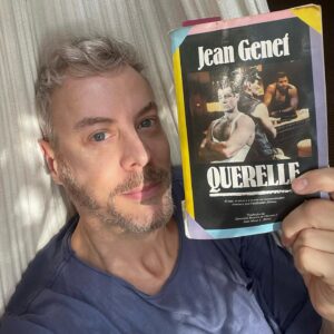 Guilherme Weber Instagram - Beleza avassaladora. Hoje terminei Querelle, que com Nossa Senhora das Flores e Diário de um Ladrão, constitui a santíssima trindade do francês. Ele é hoje um dos meus romancistas favoritos. Opositor do pudor, Genet entrega o personagem como epifania. “Seria preciso que pressentíssemos em nós mesmos a existência de Querelle.”
Ele vive de todas as maneiras que considera bela; sexo na neblina, destroçando corações, matando e roubando. E amando como uma atriz de opereta.
Genet fala com o leitor de maneira Machadiana neste romance, alterna os narradores de maneira vertiginosa, à facadas e confunde toda a nossa experiência onírica com realidade. 
As páginas ficarão comigo para sempre. Seu protagonista, uma camiseta jogada no chão como se fosse um leopardo pronto para dar o bote e as dilacerantes maneiras de amar de outros dois personagens fascinantes, o tenente Seblon, fazendo de banheiros públicos seu altar de oração e Madame Lysiane, de cabelos despenteados, amando entre lágrimas e catarros.
Querelle termina como um poema amoroso mas também como uma ponte inalcançável entre desejos e tantos objetos ausentes. E depois de 265 viradas de página faz-se morada, fruição, estância.
“Minha vulgaridade é real e me concede todos os direitos.”
#jeangenet #querelle