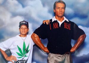 Henry van Loon Instagram - Ergens halverwege de jaren 90 deden we een ‘dagje Amsterdam’, Toen had je daar nog de ‘madame Tussauds’ dat was toen heel vet. Ondanks dat wat op zijn shirt staat, is Arnie helemaal niet echt. Ik daarentegen wel. Ik had nog nooit van wiet gehoord en het duurde nog minstens 10 jaar voordat ik het ooit zou proberen. #thosewerethedays @schwarzenegger @madametussaudsamsterdam @newyorkgiantsclubhousedotcom #precorona ❤️amsterdam. Verder gaat het goed.