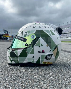 Jack Aitken Instagram - I proudly present to you the latest Aitken x Koop collab, courtesy of @stilo_official. The Thistle. 🌷

Inspiration came from the classic emblem of Scotland, the thistle, a prickly yet beautiful flower that blooms bright purple from the cold greens and greys of the British countryside. The little dashes of gold were thrown in to set off the muted greens and bright purples. On the back we have the motto of The Order of the Thistle (yes it’s a thing), which translates to “Nobody attacks me with impunity”, referring to our prickly nature. Let’s hope that rings true this season 😉 I’m glad to see it’s already been given the thumbs up by a few of you (swipe to the end)! 

#BeIconic #CadillacRacing 

Final pic 📸 @bcpix
